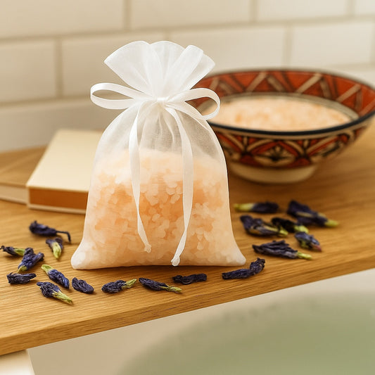 Organza pouch filled with Himalayan salt and butterfly pea flowers, tied neatly with a bow, surrounded by dried blue petals.