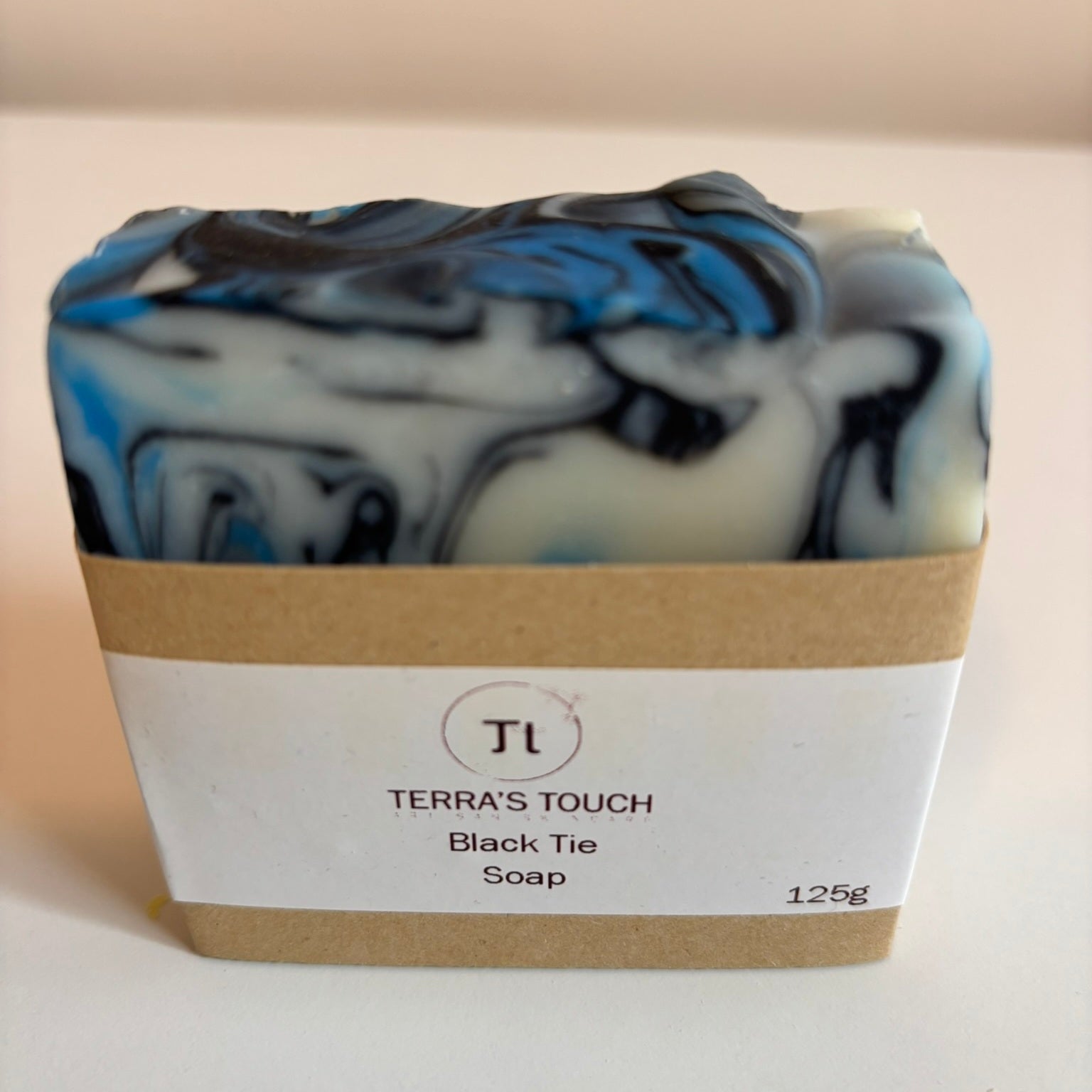 Handmade marbled soap with blue, black and cream swirls with craft label
