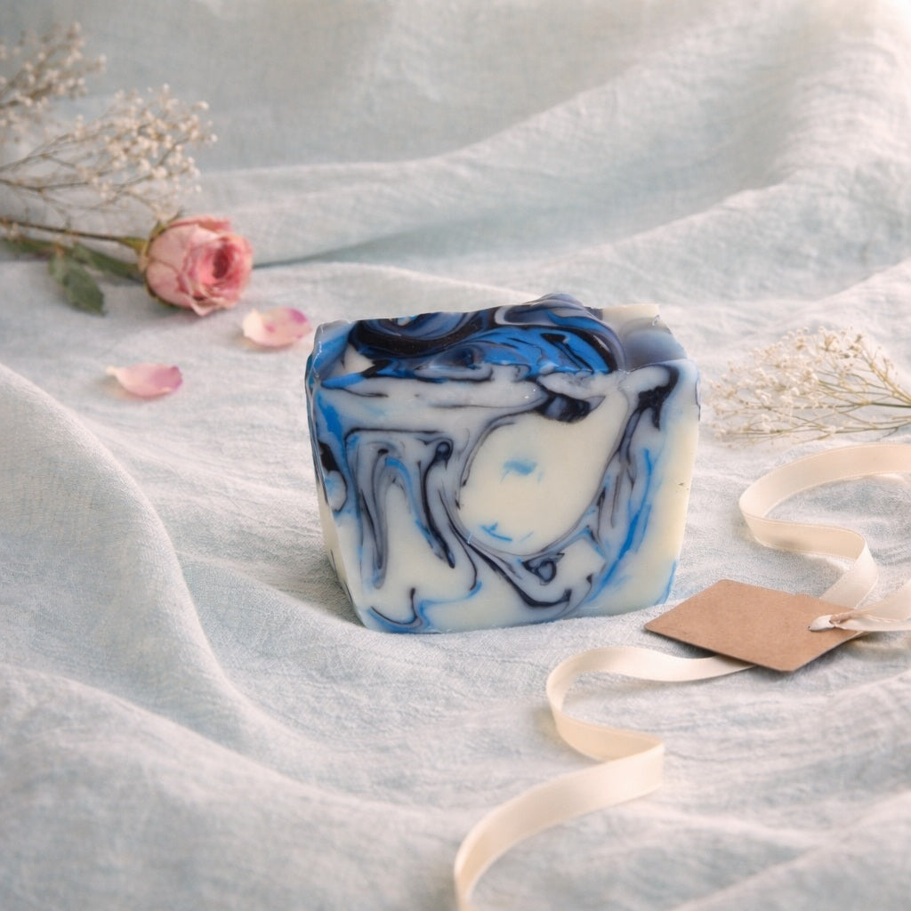 black blue and white marbled handmade soap on an aqua linen with pink rose and ribbon