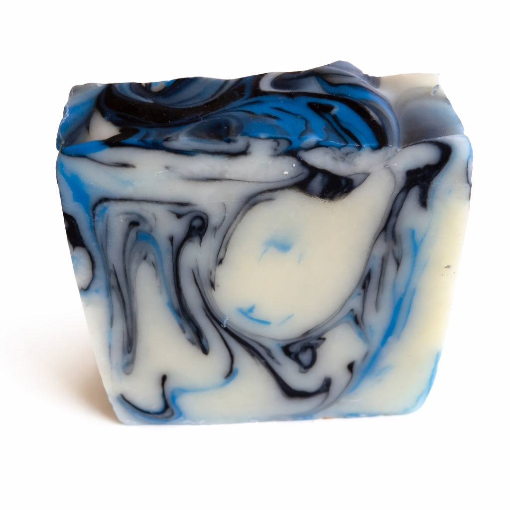 Handmade marbled soap with blue, black and cream swirls photographed on a white background
