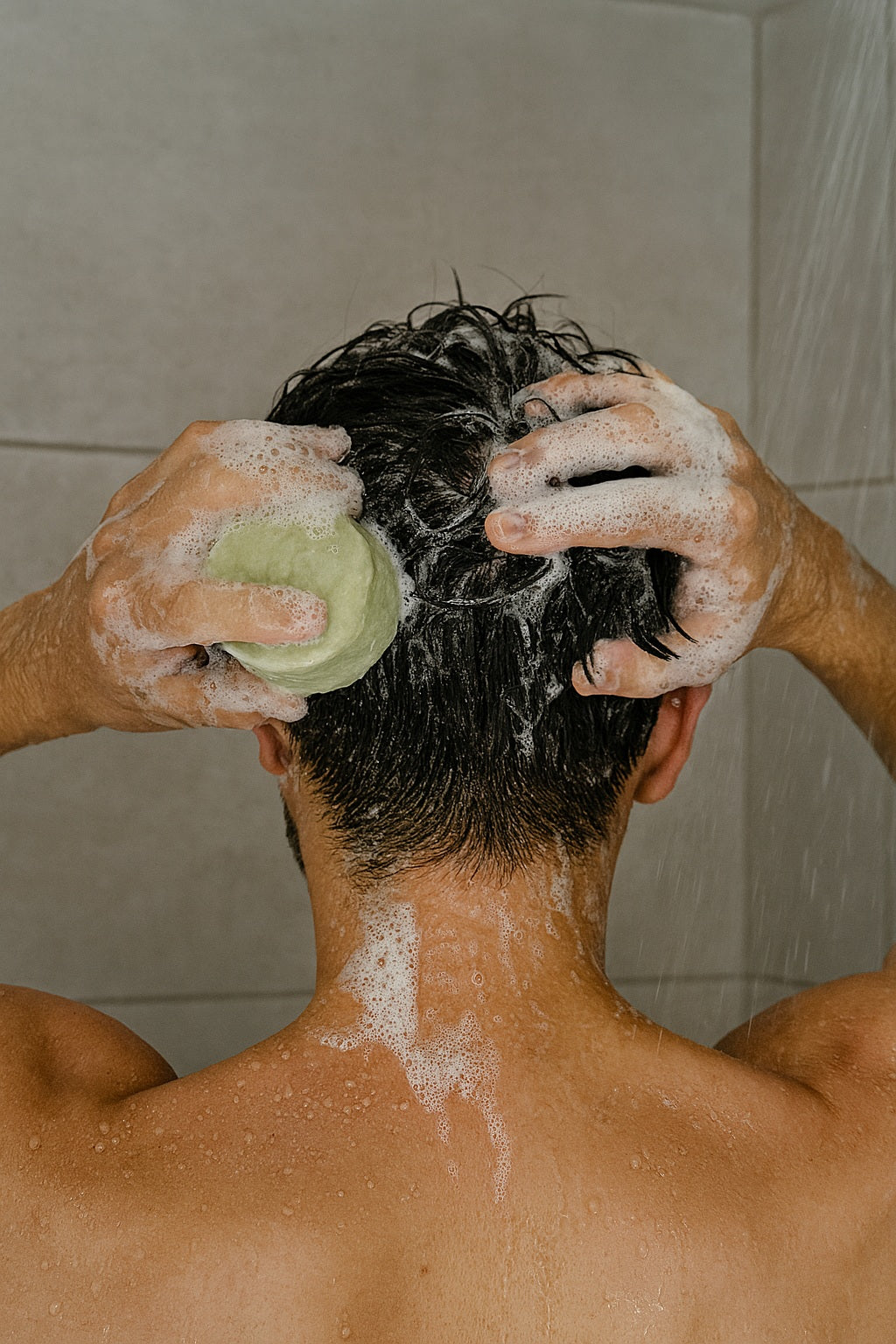 man in the shower washing its hair with shampoo bar