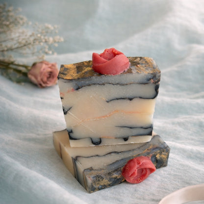 2 handmade marbled soaps with rose on top on a aqua linen and pink rose