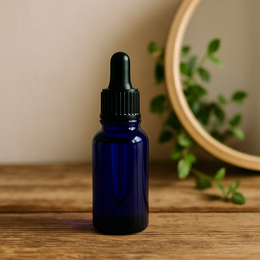 pomegranate facial oil in a blue bottle with dropper on a wooden table with mirror an green plangt