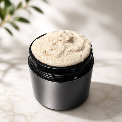 black jar of emulsified sugar scrub on a white marble background