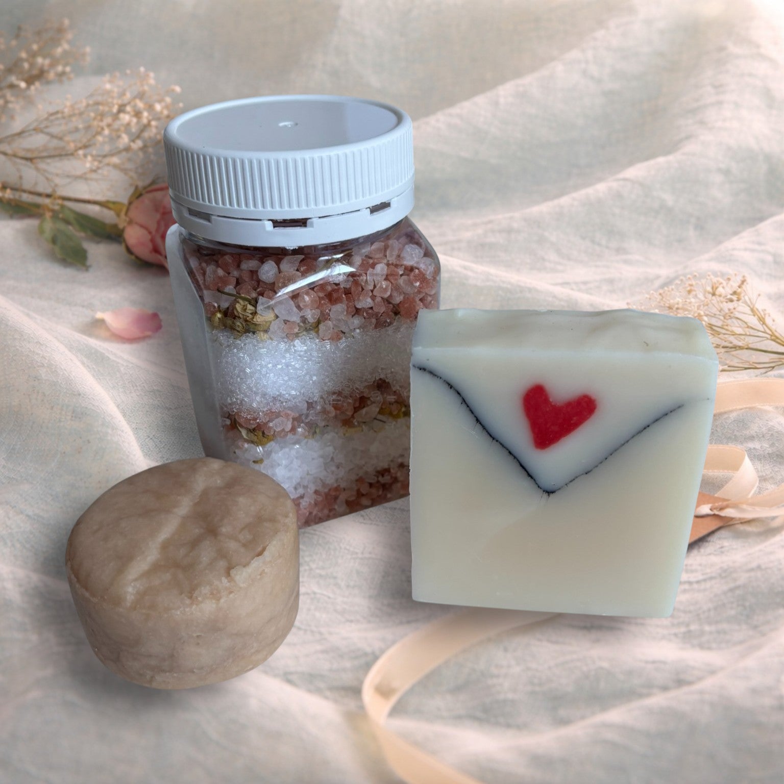 bath soak, shampoo bar and bar of soap on a valentine decor of aqua linen, pink roses and ribbon