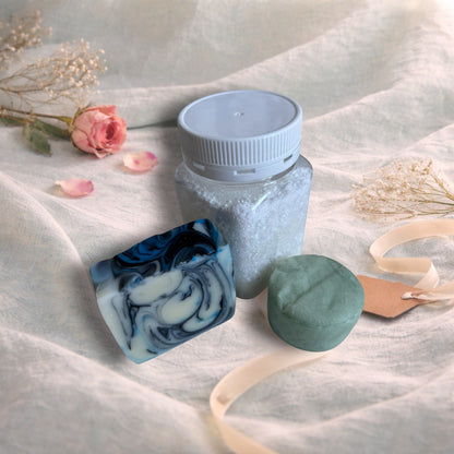 bath soak, shampoo bar and bar of soap on a valentine decor of aqua linen, pink roses and ribbon
