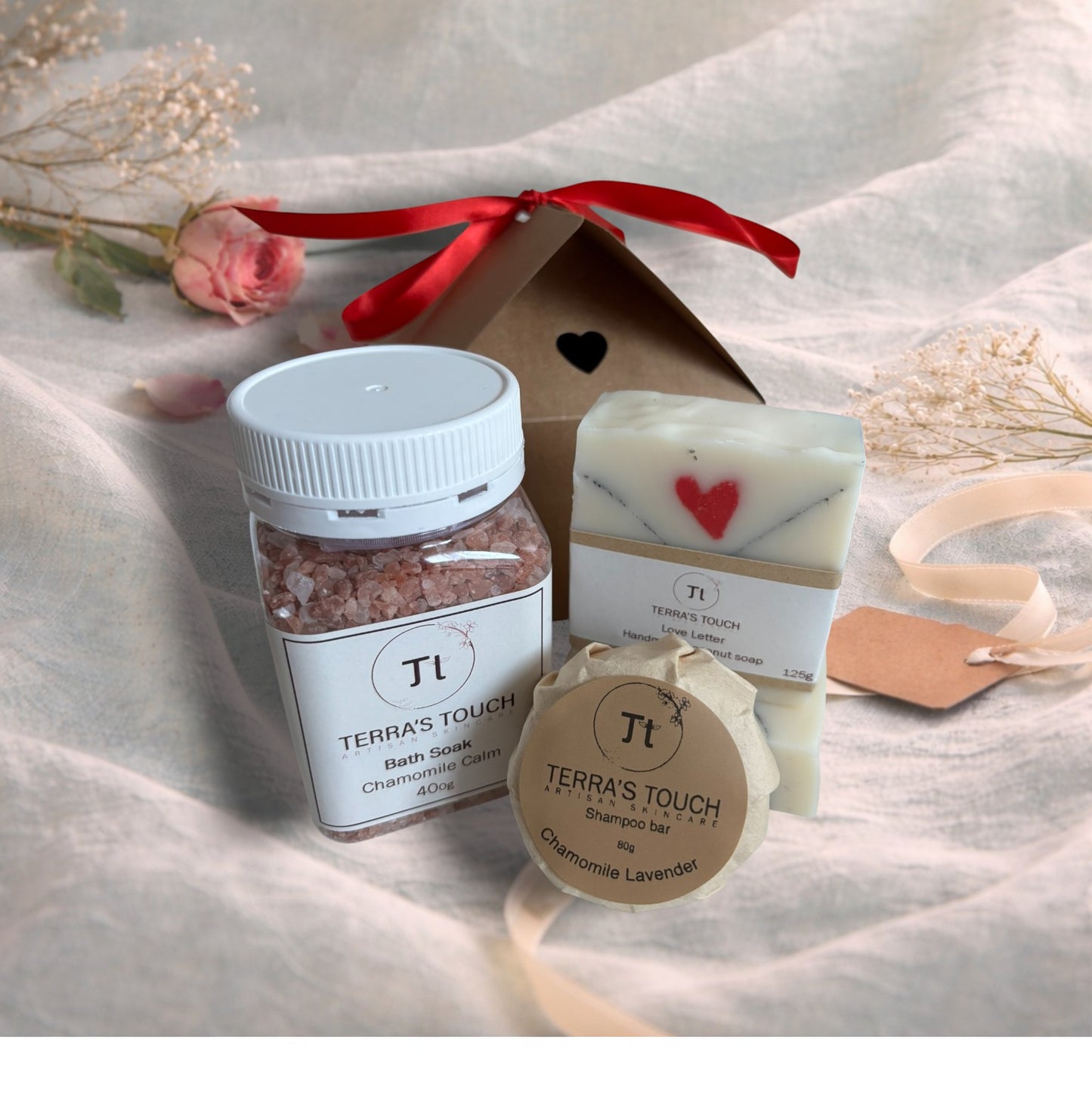 bath soak, shampoo bar and bar of soap on a valentine decor of aqua linen, pink roses and craft box