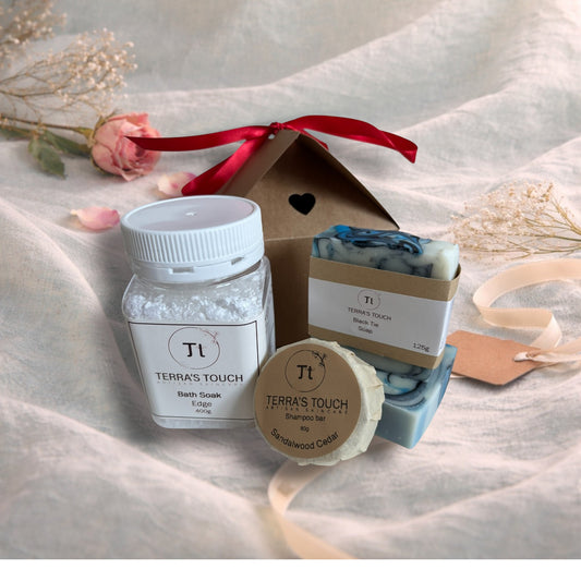 bath soak, shampoo bar and bar of soap on a valentine decor of aqua linen, pink roses and craft box